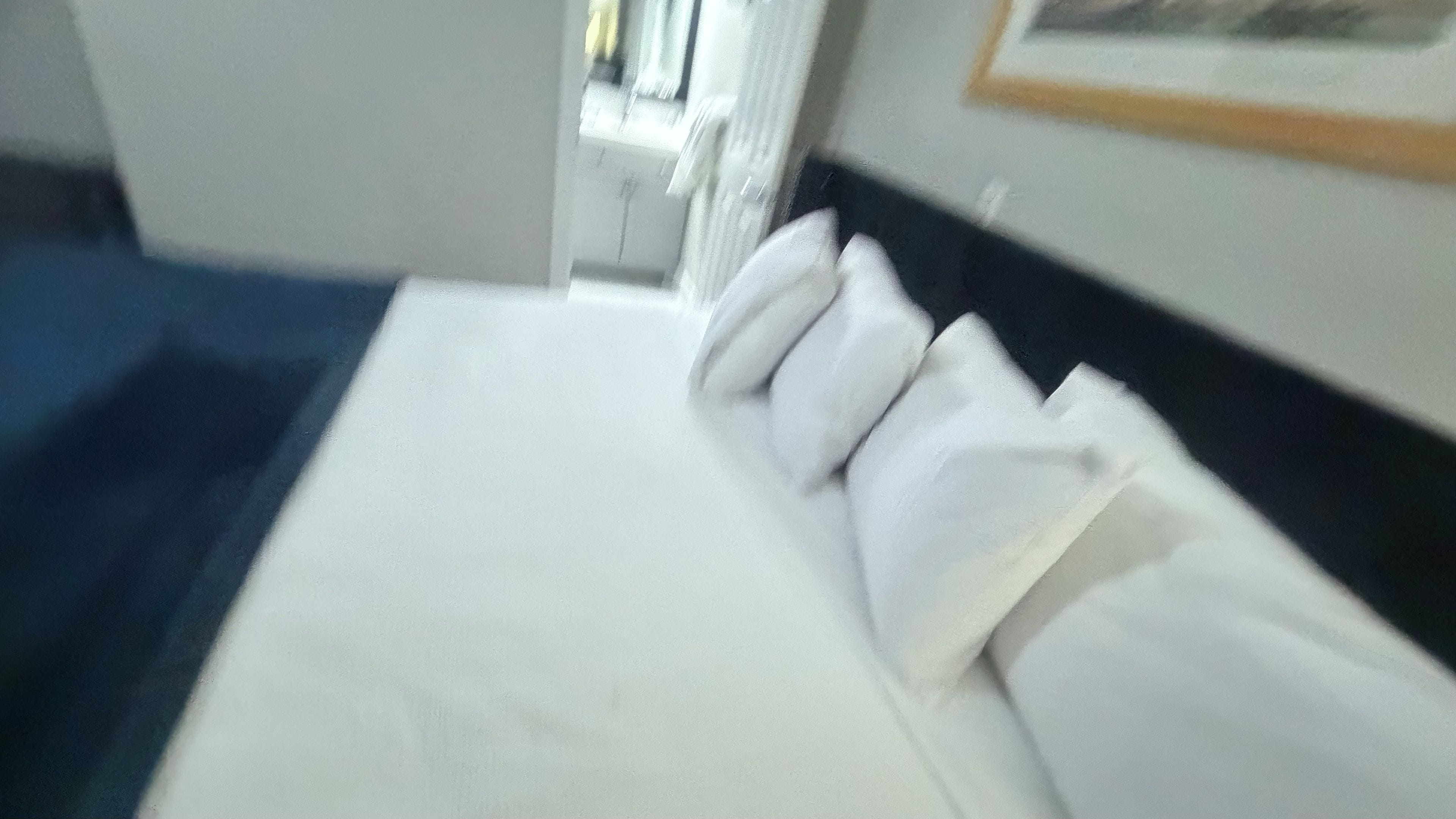 Habitació d'hotel amb un llit, almoines, un capçal i un quadre a la paret.