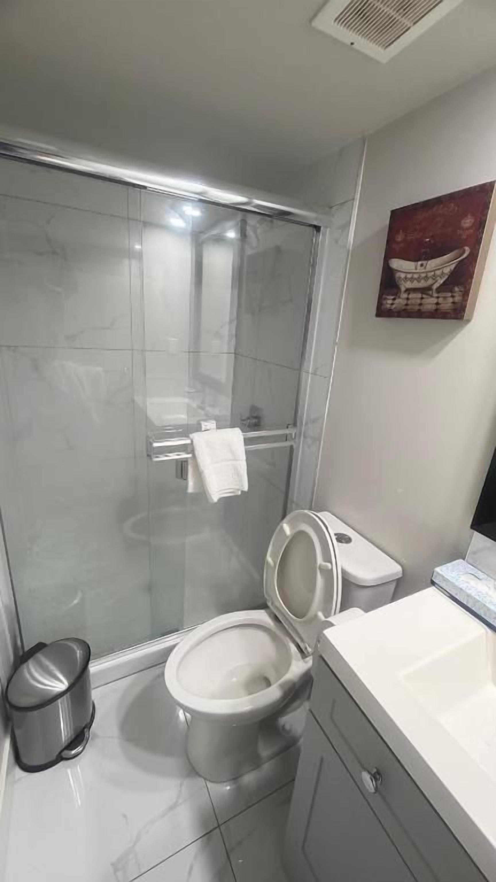 A bathroom with a glass-enclosed shower, a toilet, and a sink.