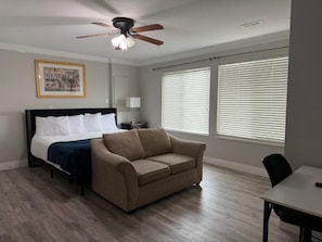 A bedroom with a bed, a sofa, a ceiling fan, and large windows with blinds. - J & J Dream Villa Ltd (Abbotsford)