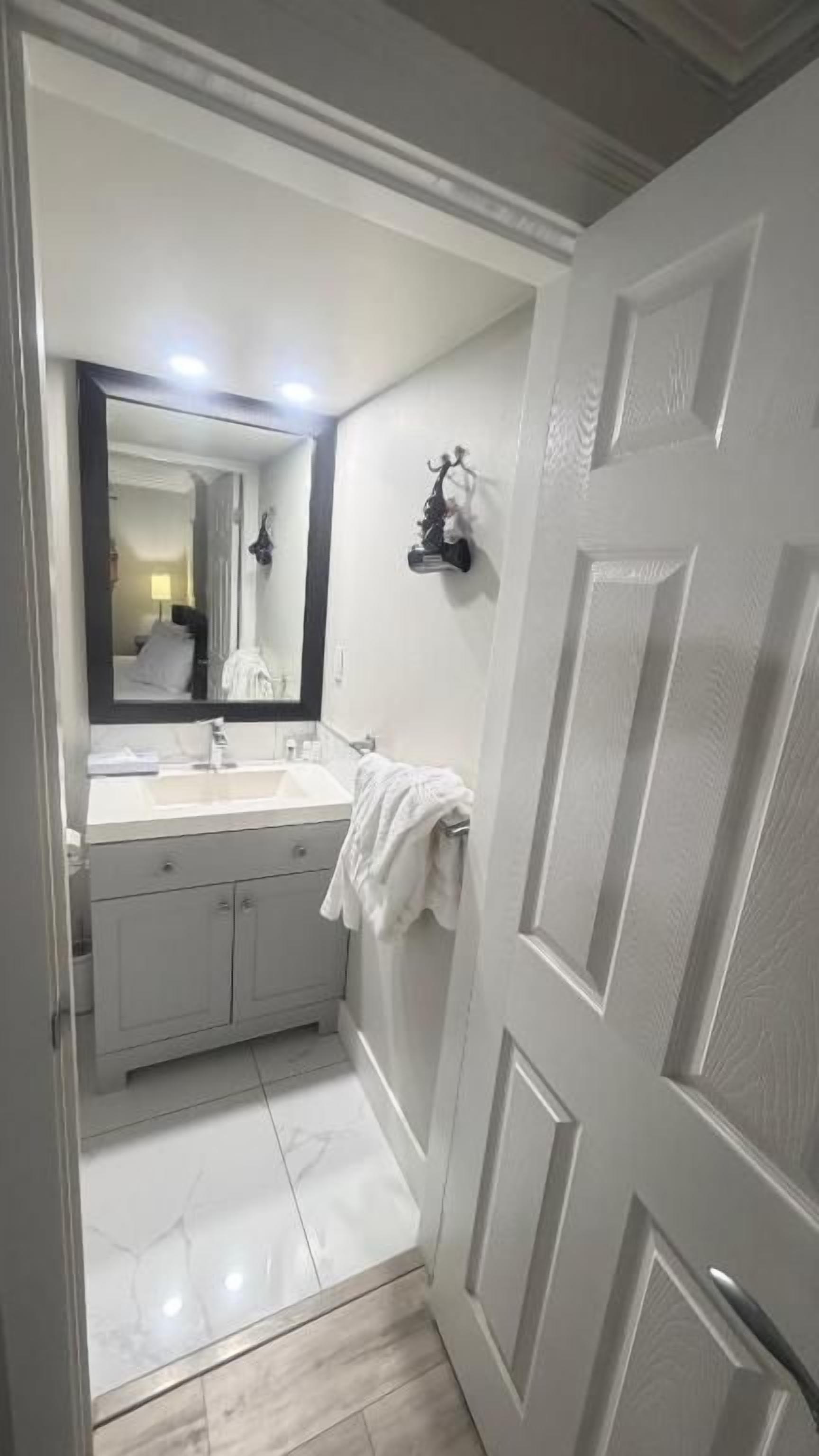 A bathroom with a white vanity, a mirror, and a towel rack.