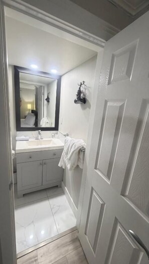 A bathroom with a white vanity, a mirror, and a towel rack. - J & J Dream Villa Ltd (Abbotsford)