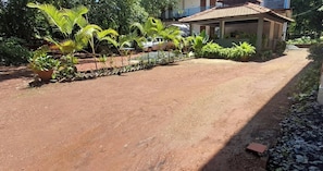 A dirt path leading to a house with a tiled roof, surrounded by lush greenery and potted plants. - Room-peaceful Stay Private Studio R-11 1 (Arambol)