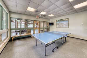 Ett bordtennisbord i ett rum med utsikt över en byggnad genom stora fönster.