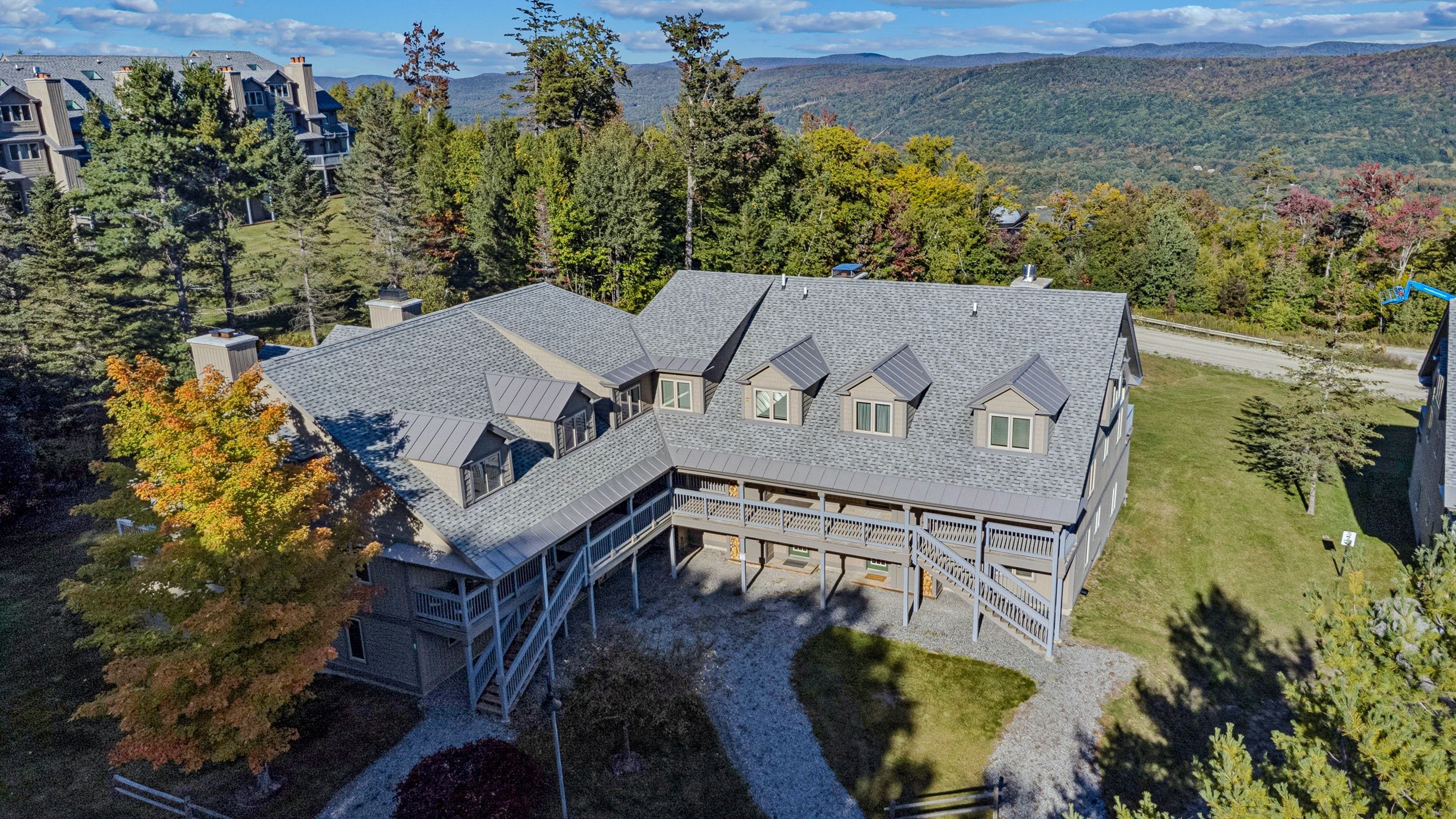 A large, multi-story house with a sloped roof, surrounded by a well-maintained lawn and trees.