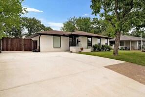 A single-story house with a covered patio area, a fenced yard, and a tree. - Near AT&T Stadium | Parking | Pets OK (Arlington)