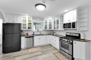 A modern kitchen with white cabinetry, stainless steel appliances, and a granite countertop. - Near AT&T Stadium | Parking | Pets OK (Arlington)