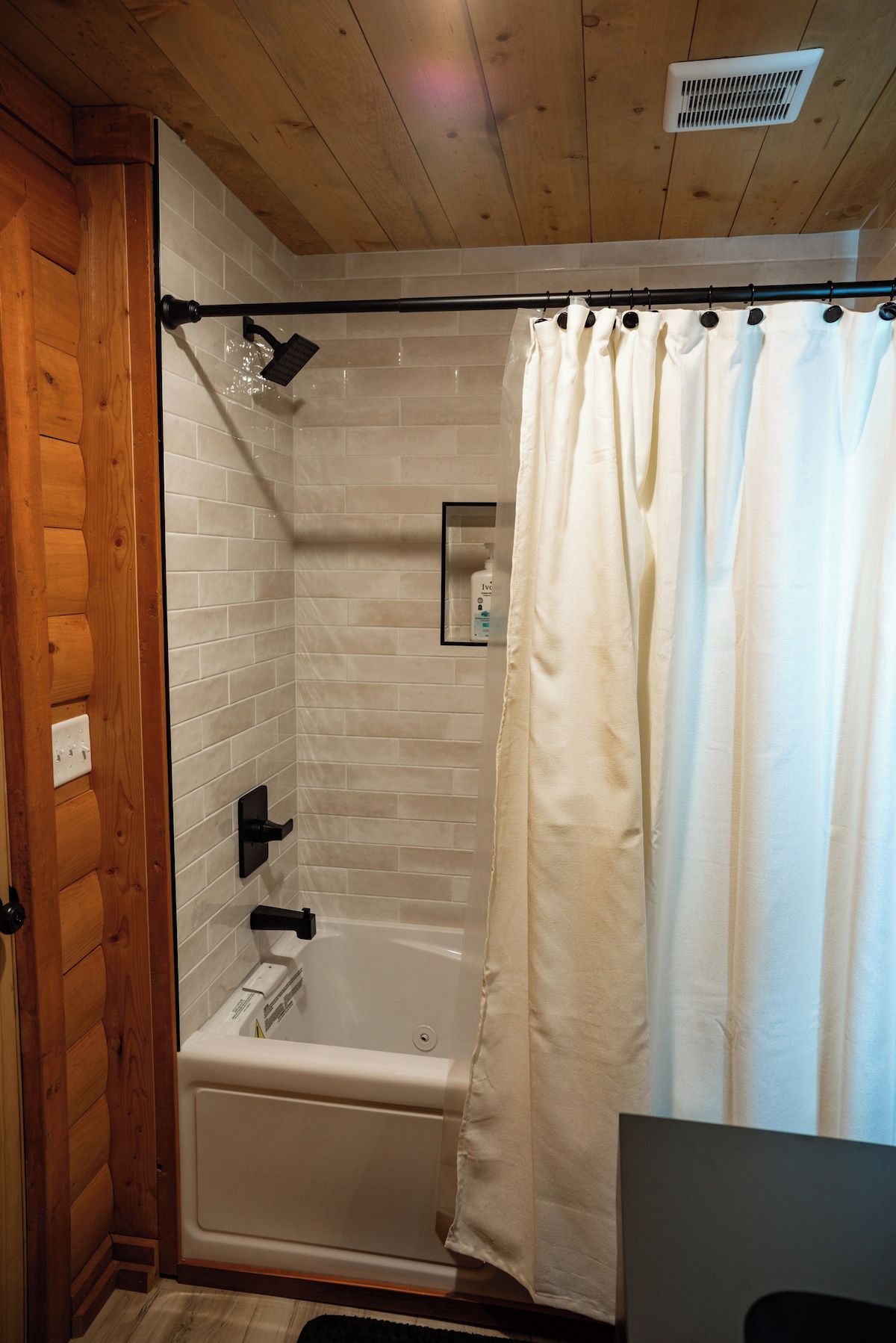 Ein Badezimmer mit Badewanne, Duschkopf, Handtuchhalter und einer Vorhang.