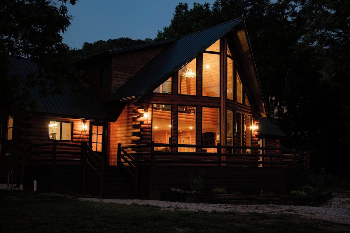 A log cabin with a prominent front porch and large windows.