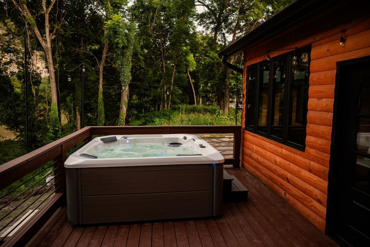A hot tub on a wooden deck with a view of a forested area.