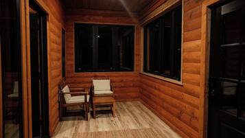 A wooden cabin interior with a bench, a table, and a large window.