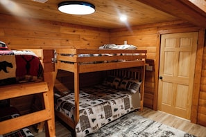 Ein Zimmer in einer Holzhütte mit Etagenbetten, einer Tür und einer Deckenleuchte.