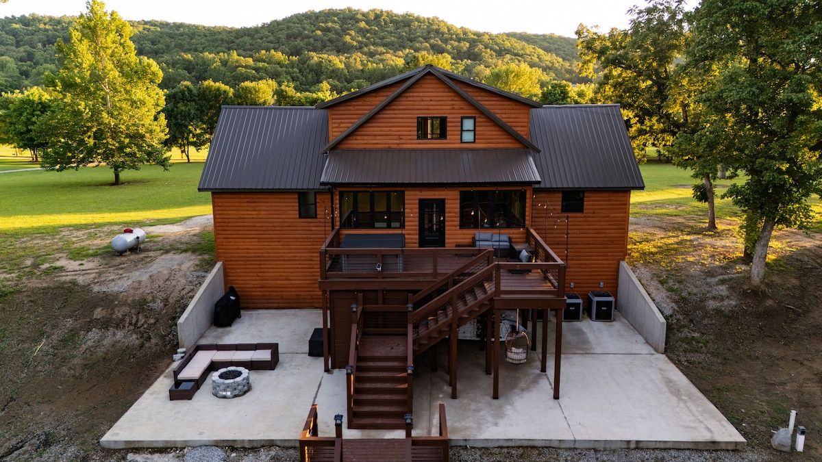 A wooden cabin with a deck, a staircase, and a concrete patio.