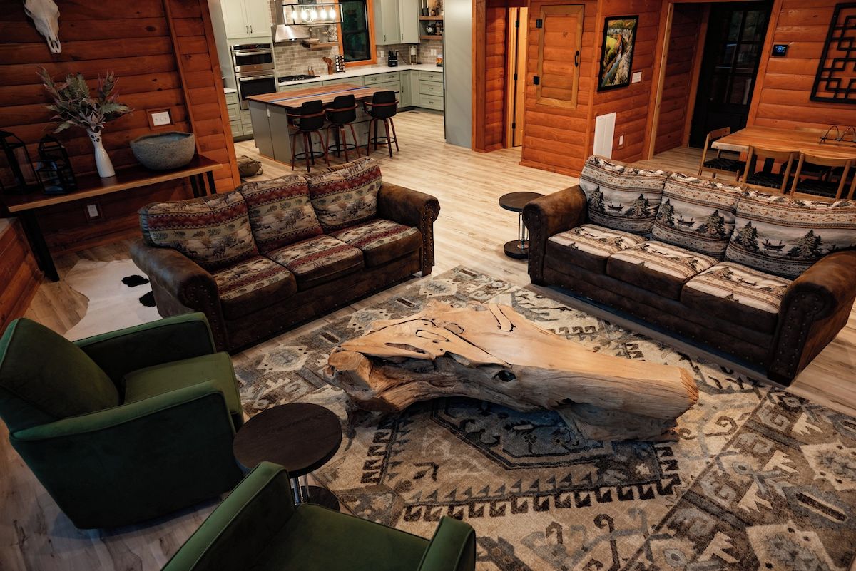 A log cabin interior with a living room, kitchen, and dining area.