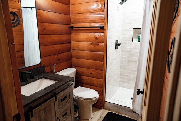 A wooden-paneled bathroom with a sink, toilet, and shower.