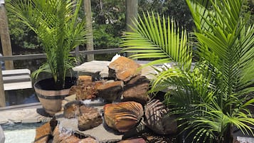 A rock waterfall feature surrounded by potted plants and a wooden fence.