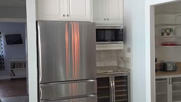 A kitchen with white cabinets, stainless steel appliances, and a wooden floor.