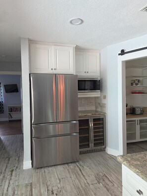 A kitchen with white cabinets, stainless steel appliances, and a wooden floor.
