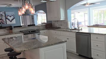 A modern kitchen with a large island, white cabinetry, and a hanging light fixture.
