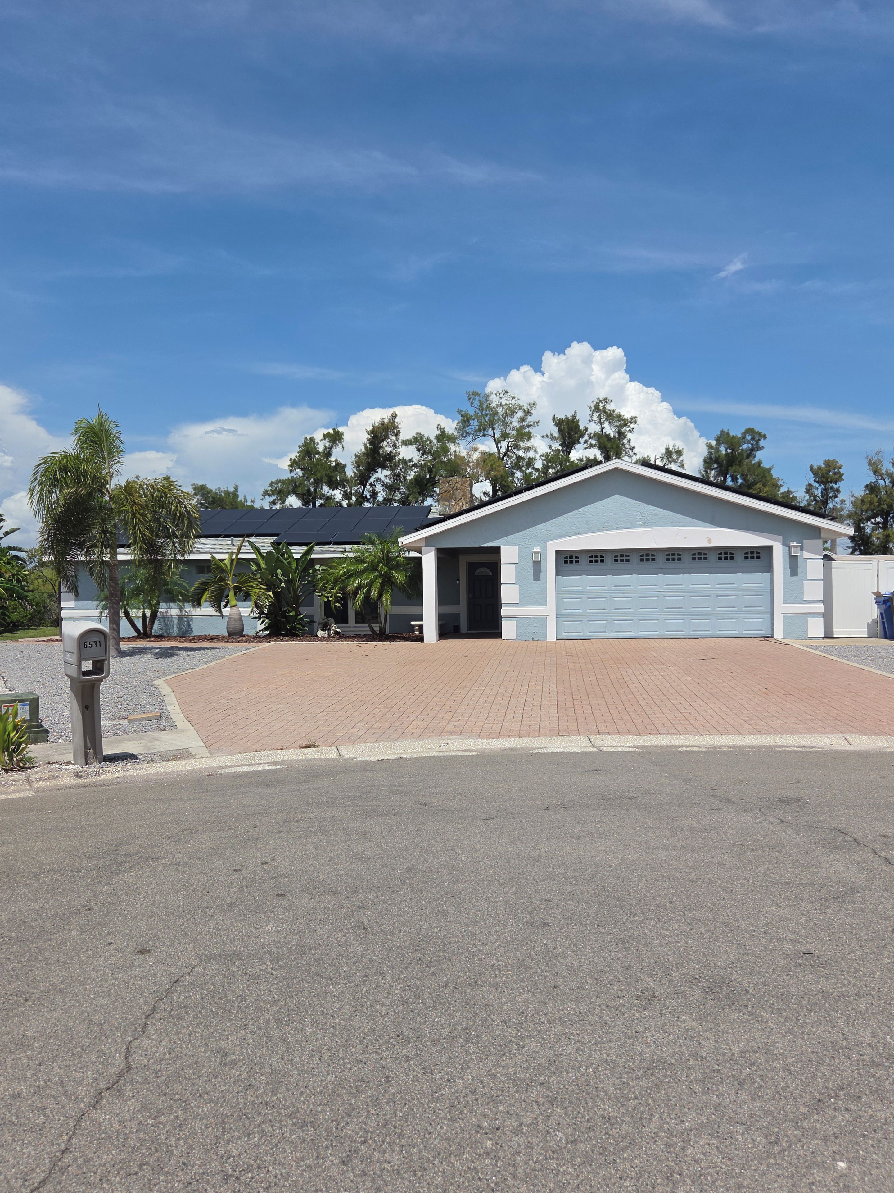 A single-story building with a garage, a paved driveway, and a mailbox.