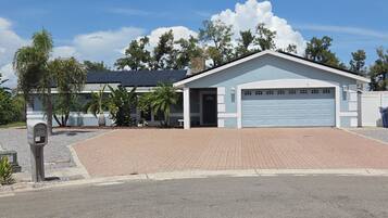 A single-story building with a garage, a paved driveway, and a mailbox.