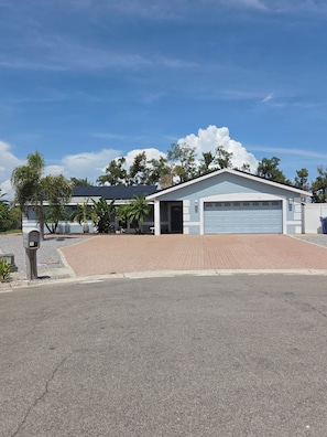 A single-story building with a garage, a paved driveway, and a mailbox.