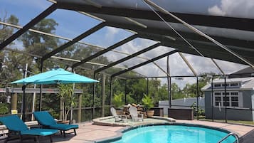 A covered outdoor swimming pool with lounge chairs and a patio area.