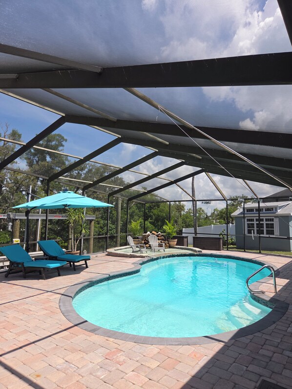 A covered outdoor swimming pool with lounge chairs and a patio area.