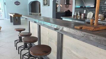 A bar area with stools, a ceiling fan, and a dartboard on the wall.