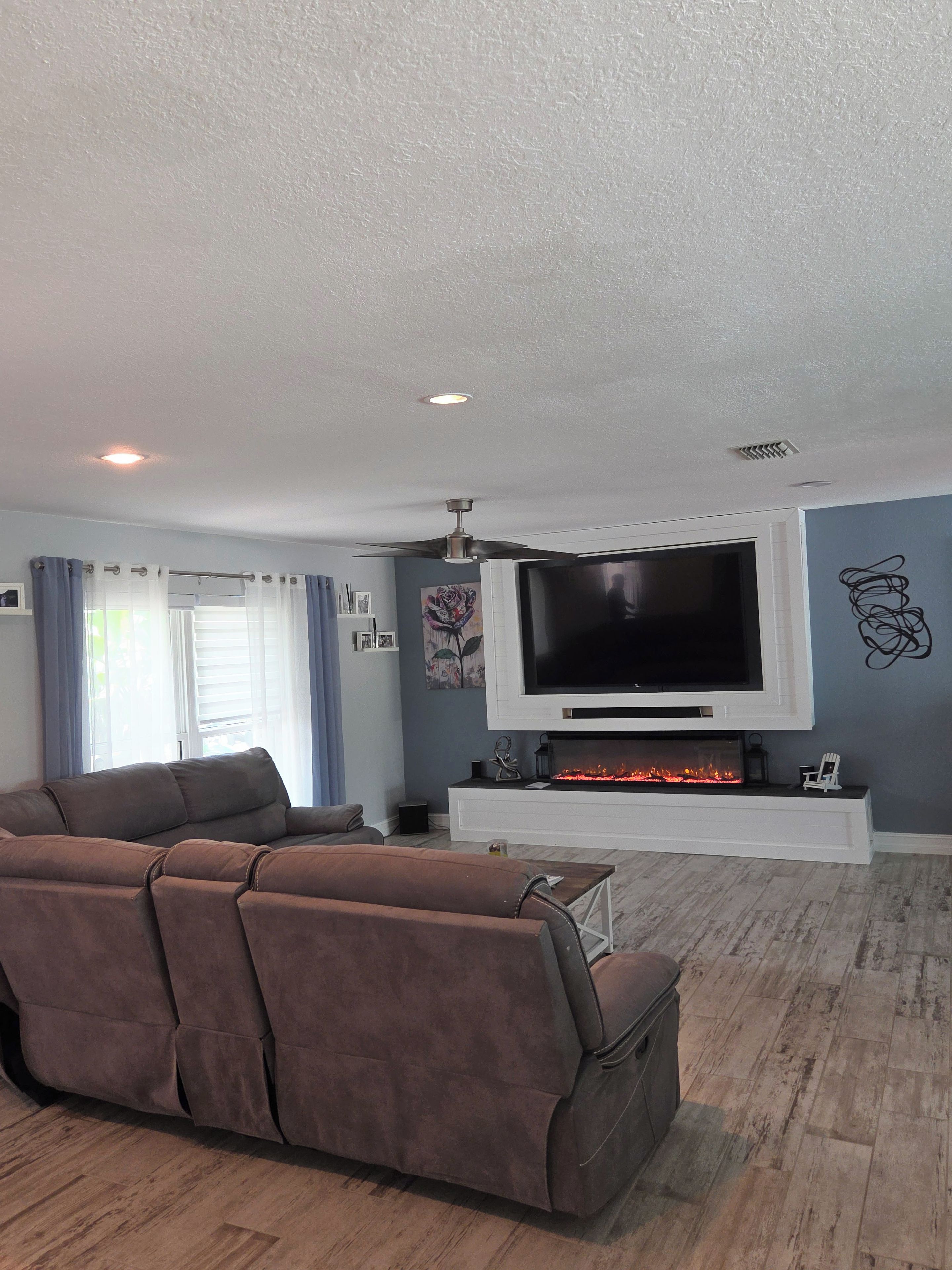 A living room with a large flat-screen TV, a fireplace, and a sofa.