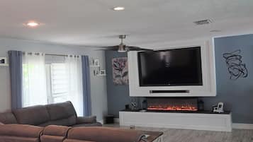 A living room with a large flat-screen TV, a fireplace, and a sofa.