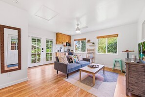 Ein großzügiger Wohnbereich mit grauem Sofa, Holzböden und einem Deckenventilator.