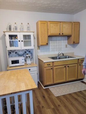 A kitchen with wooden cabinets, a white countertop, a microwave, and a sink. - Peaceful 1-bedroom back house with AC in charming Versailles (Versailles)