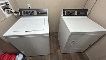 Two front-loading washing machines in a laundry room with a wooden floor.