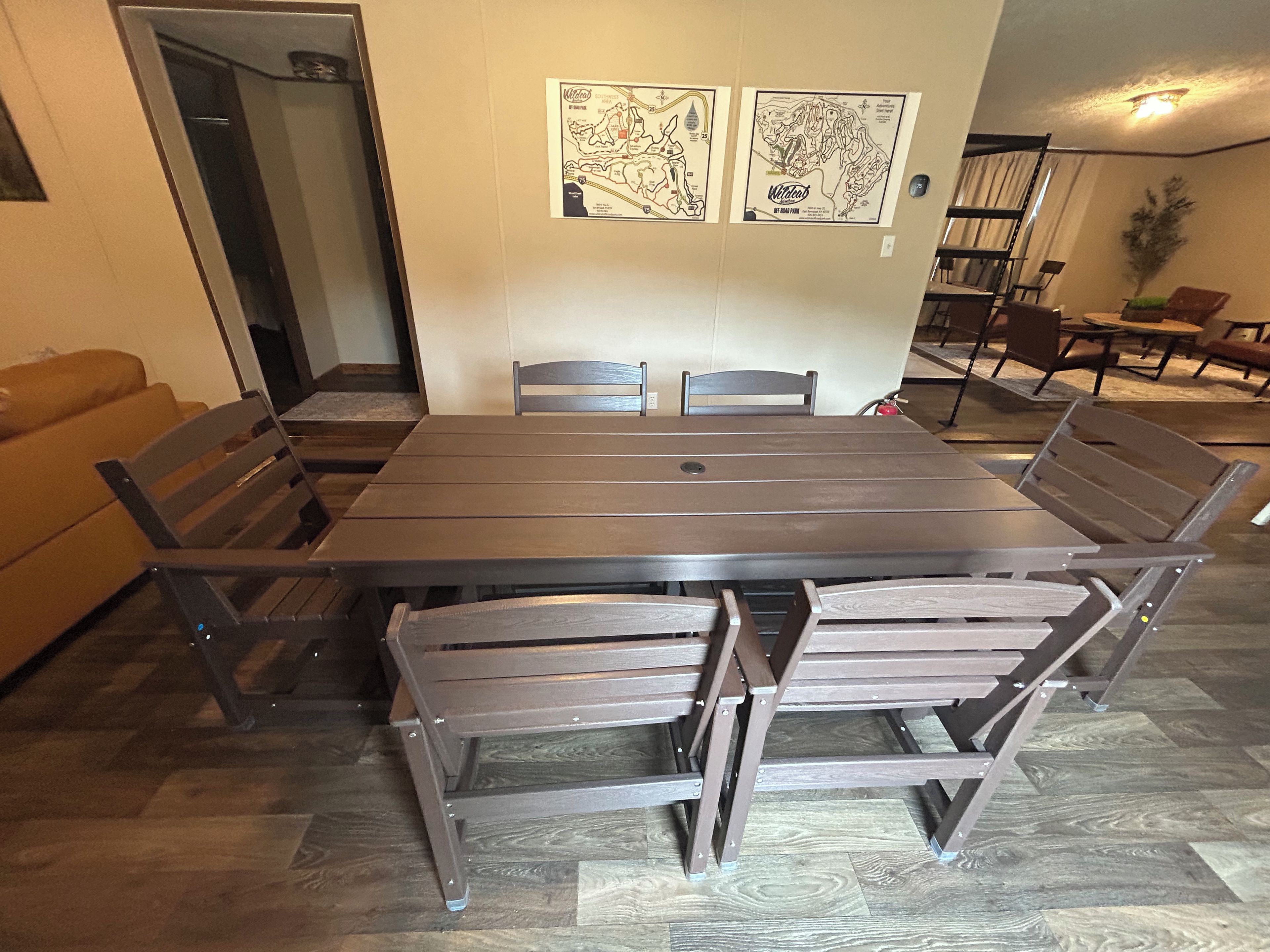 Een eetruimte met een rechthoekige tafel en zes stoelen. Daarboven hangen aan de muur twee ingelijste kaarten.