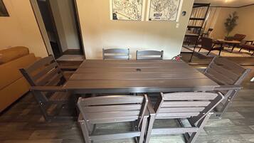Een eetruimte met een rechthoekige tafel en zes stoelen. Daarboven hangen aan de muur twee ingelijste kaarten.