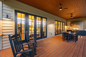 A covered patio with wooden flooring, outdoor seating, and a kitchen area with a grill. - Balsam Preserve Private Golf Resort | Luxury w/ Mtn Views (Sylva)