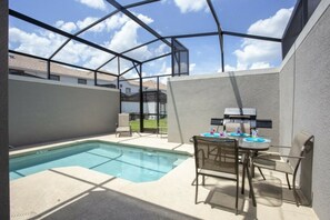 A backyard with a swimming pool, a barbecue grill, and a table with chairs. - 5BR Storey Lake | Pool, Mickey & Minions rooms (Kissimmee)