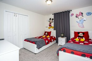A bedroom with two beds, each with Mickey Mouse-themed bedding, a white wardrobe, and a ceiling light fixture. - 5BR Storey Lake | Pool, Mickey & Minions rooms (Kissimmee)