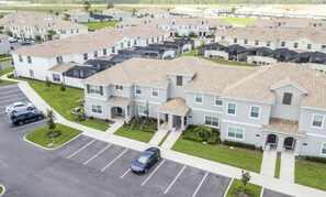 A residential area with multiple two-story houses, a parking lot, and a clear sky. - 5BR Storey Lake | Pool, Mickey & Minions rooms (Kissimmee)