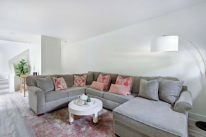 Ein Wohnzimmer mit grauem Sofa, einem weißen Couchtisch und einem gemusterten Teppich.