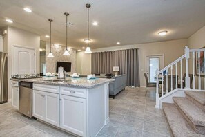 A spacious kitchen with a central island, white cabinetry, and pendant lighting. - 5BR Disney townhome | Pool & themed rooms (Kissimmee)