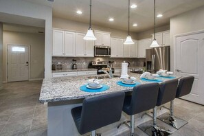 A kitchen with white cabinets, stainless steel appliances, and a granite countertop. - 5BR Disney townhome | Pool & themed rooms (Kissimmee)