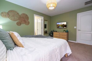 Ein Schlafzimmer mit einem Bett, einer Kommode, einer Tür und einem an der Wand hängenden Bild.
