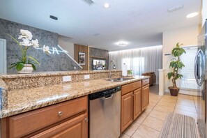 A modern kitchen with granite countertops, stainless steel appliances, and wooden cabinets. - 5BR Paradise Palms | Toy Story & Minions rooms (Kissimmee)