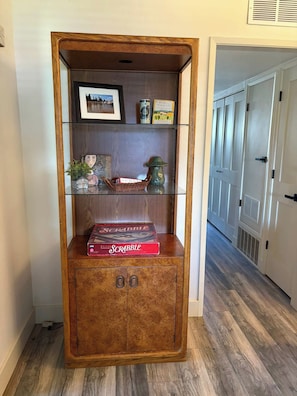 A wooden bookcase with shelves, a framed picture, and a Scrabble box. - Tahoe Keys Condo, 2 bedrooms with Boat Dock! (South Lake Tahoe)