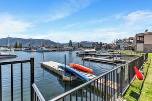 Un puerto deportivo con barcos amarrados, un muelle con kayaks y casas al fondo.