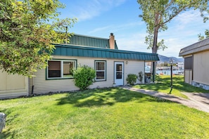 A single-story house with a green roof, a front door, and a small front yard with a tree and a bush. - Tahoe Keys Condo, 2 bedrooms with Boat Dock! (South Lake Tahoe)