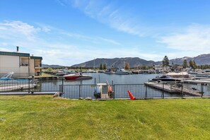A marina with boats docked, a building with a balcony, and mountains in the background. - Tahoe Keys Condo, 2 bedrooms with Boat Dock! (South Lake Tahoe)