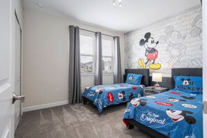 A hotel room with two beds, a Mickey Mouse mural, and a window with curtains. - 5BR ChampionsGate | Cinema, themed rooms, pool (Davenport)