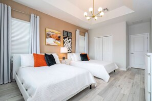 A hotel room with two beds, a chandelier, artwork on the wall, and a white door. - 6BR Sonoma Resort home | Pool & Cars game room (Kissimmee)